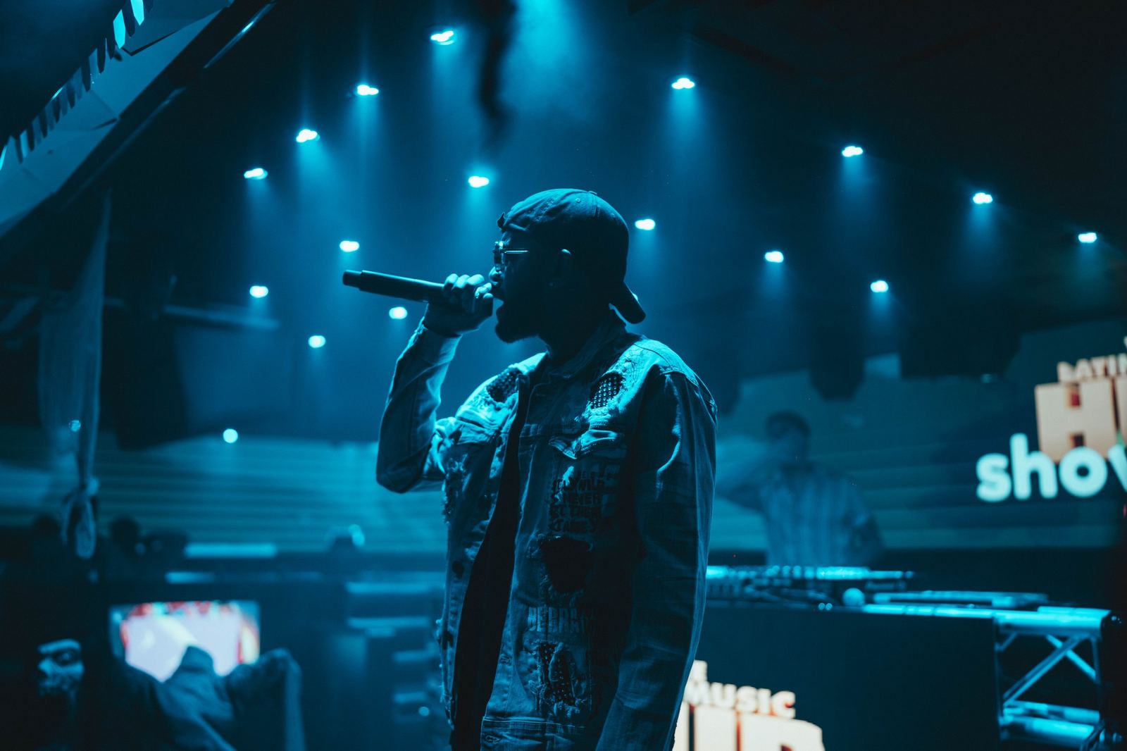 A rapper performing in silhouette under blue stage lights